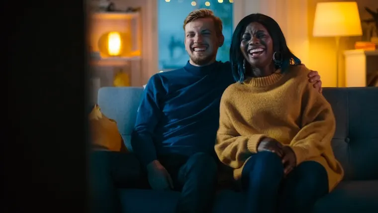 happy couple watching tv on a date at home