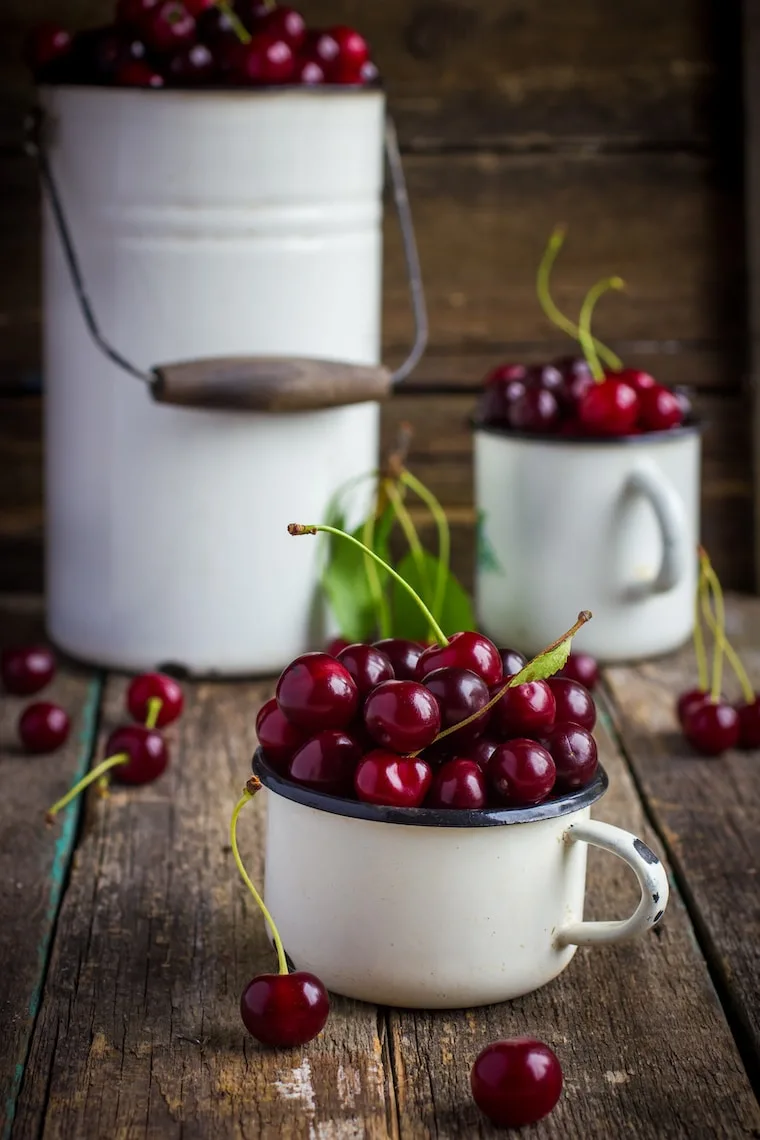 fresh cherries in enamel kitchenware on wooden background