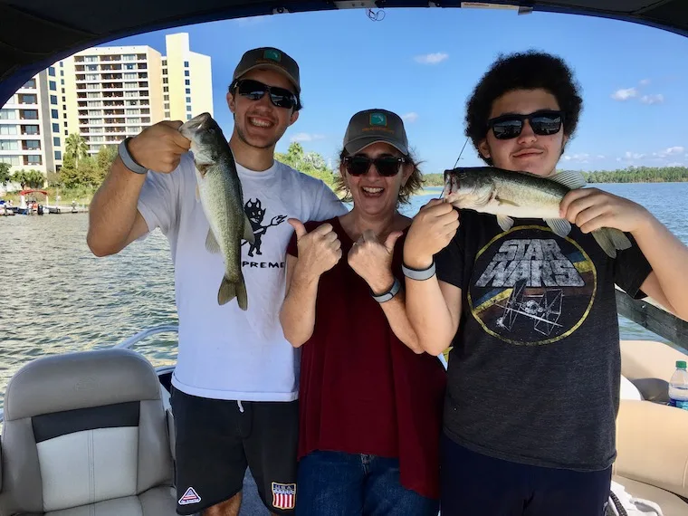 mom and 2 sons fishing and holding fish they caught