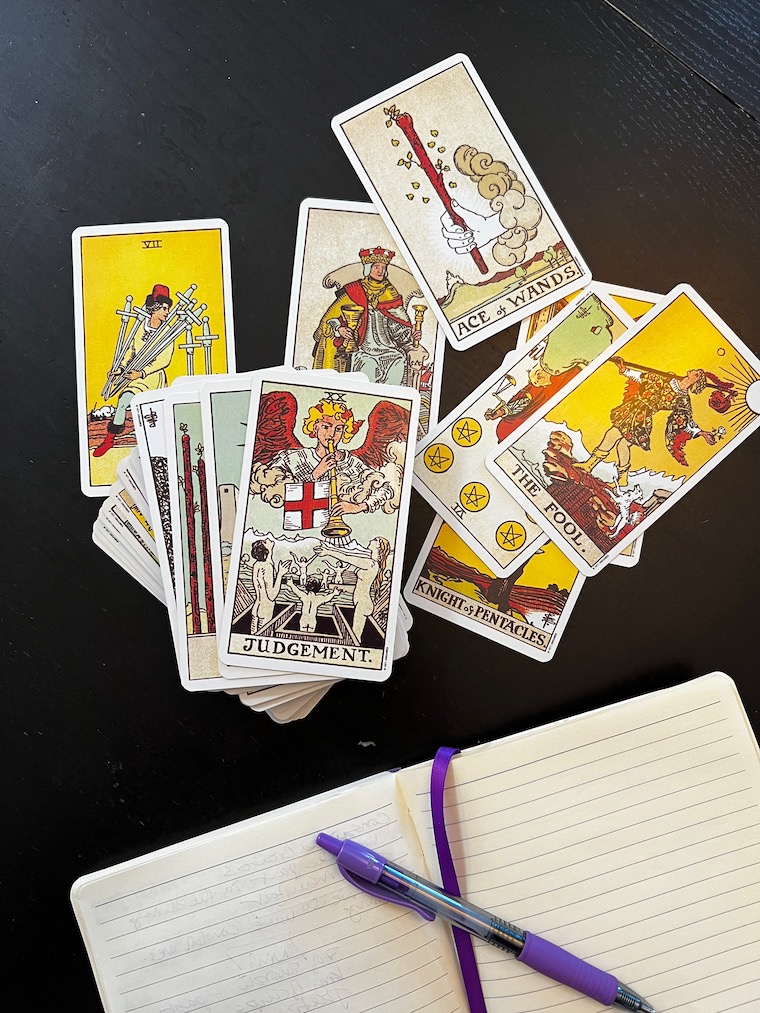 Tarot Cards spread out on a table next to a journal 