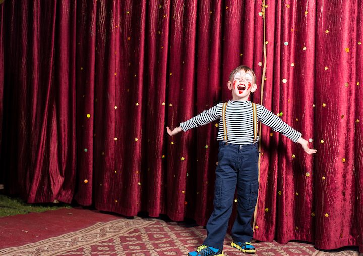 Adorable little boy singing on stage during a play