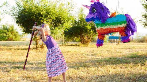 Young girl at an outdoor party hitting a pinata