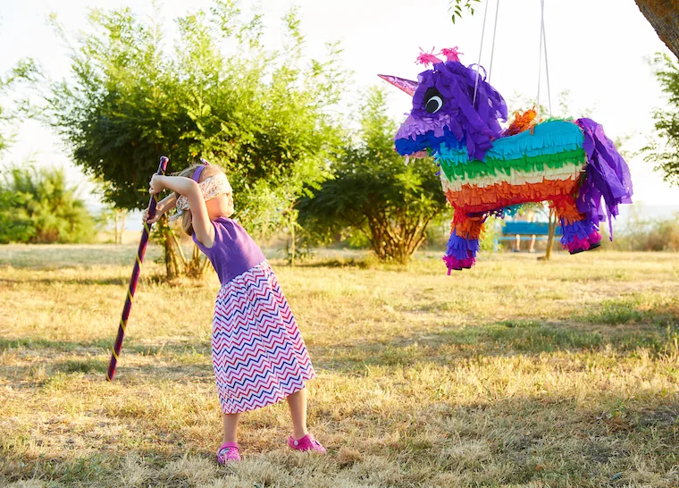 Young girl at an outdoor party hitting a pinata