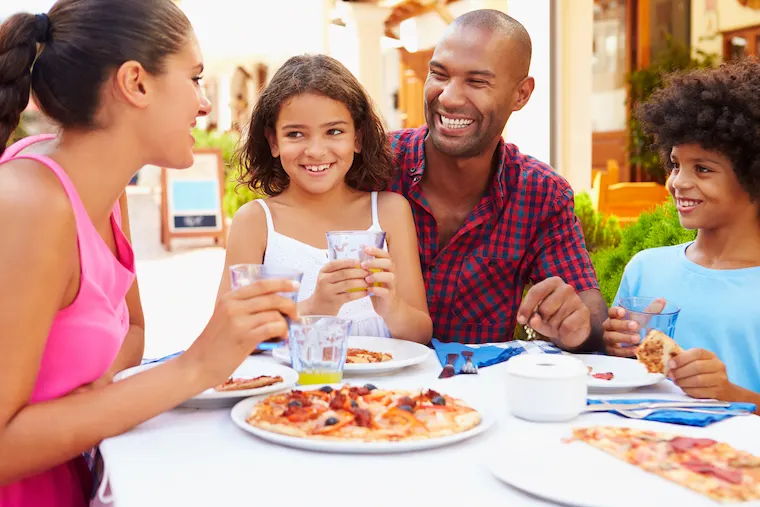 black Family Eating Meal At Outdoor Restaurant Together