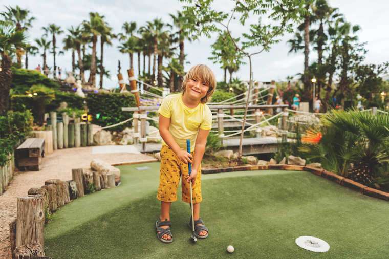 happy kid playing mini golf