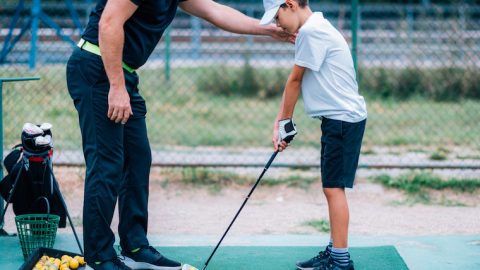Golf Lessons. Golf instructor giving game lesson to a young boy.