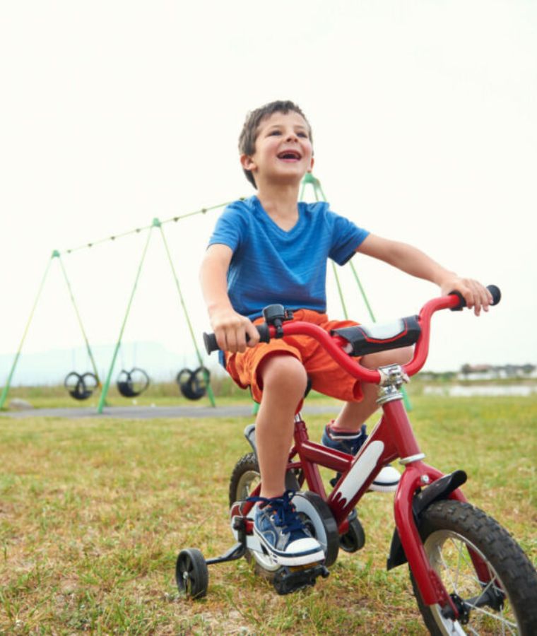 kid having fun riding a bike with training wheels