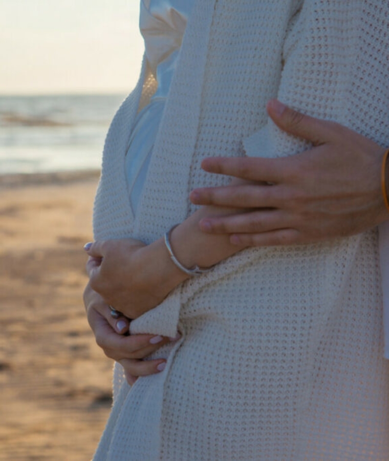 Man embracing a pregnant woman on a beach