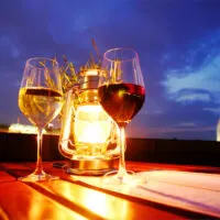 A glass of red and white wine besides a lantern.