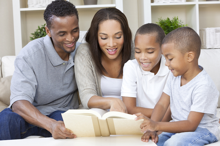 African american family of 4 reading a book together