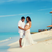 Beautiful young pregnant couple on the Caribbean coast babymoon