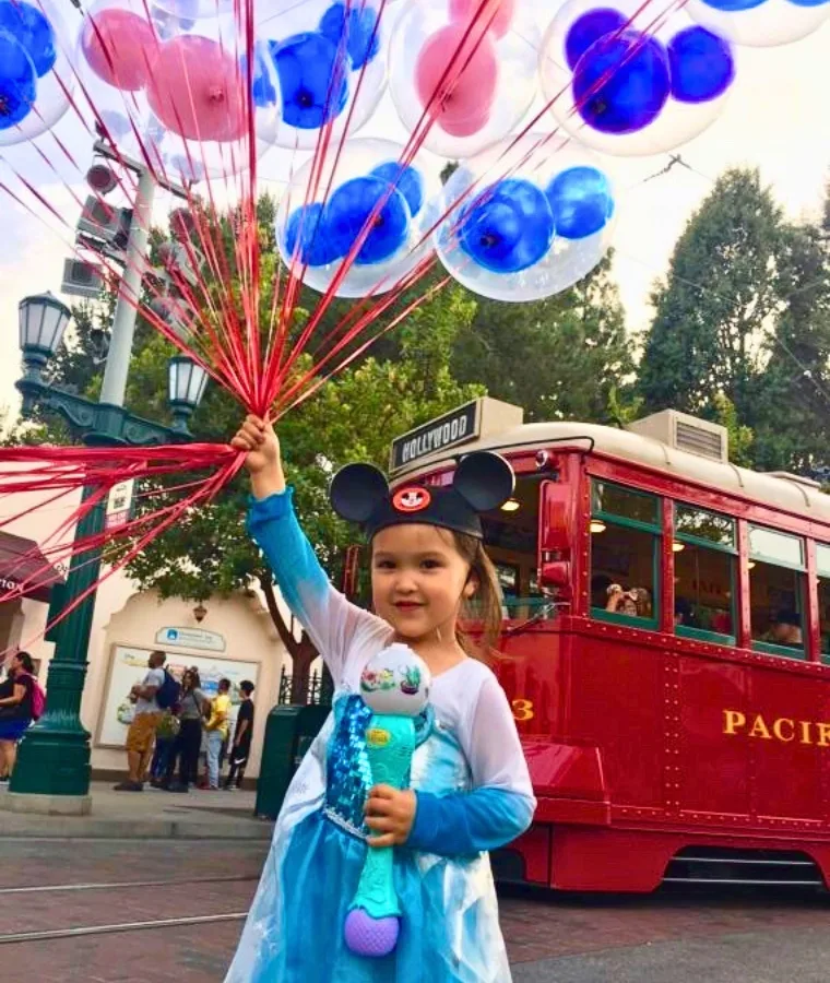 child holding balloons at Disneyland