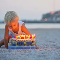 little boy on the beach with birthday cake