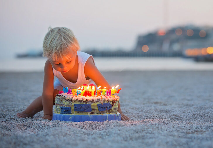 little boy on the beach with birthday cake