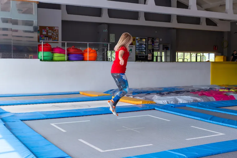 Young happy woman jumping on a trampoline indoors.