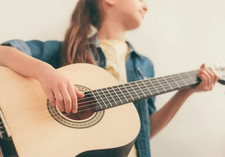 girl learning to play guitar